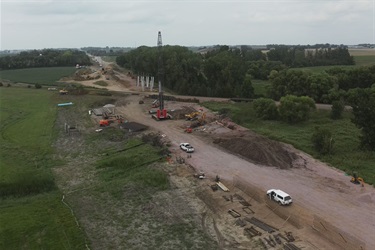 an aerial view on the project showing a crane and piles of dirt with white trucks