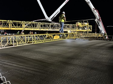 A crewman working on concrete finishing on the bridge pour