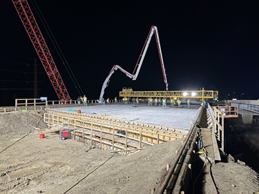 Crews pouring concrete at night on the new bridge over Cliff Ave