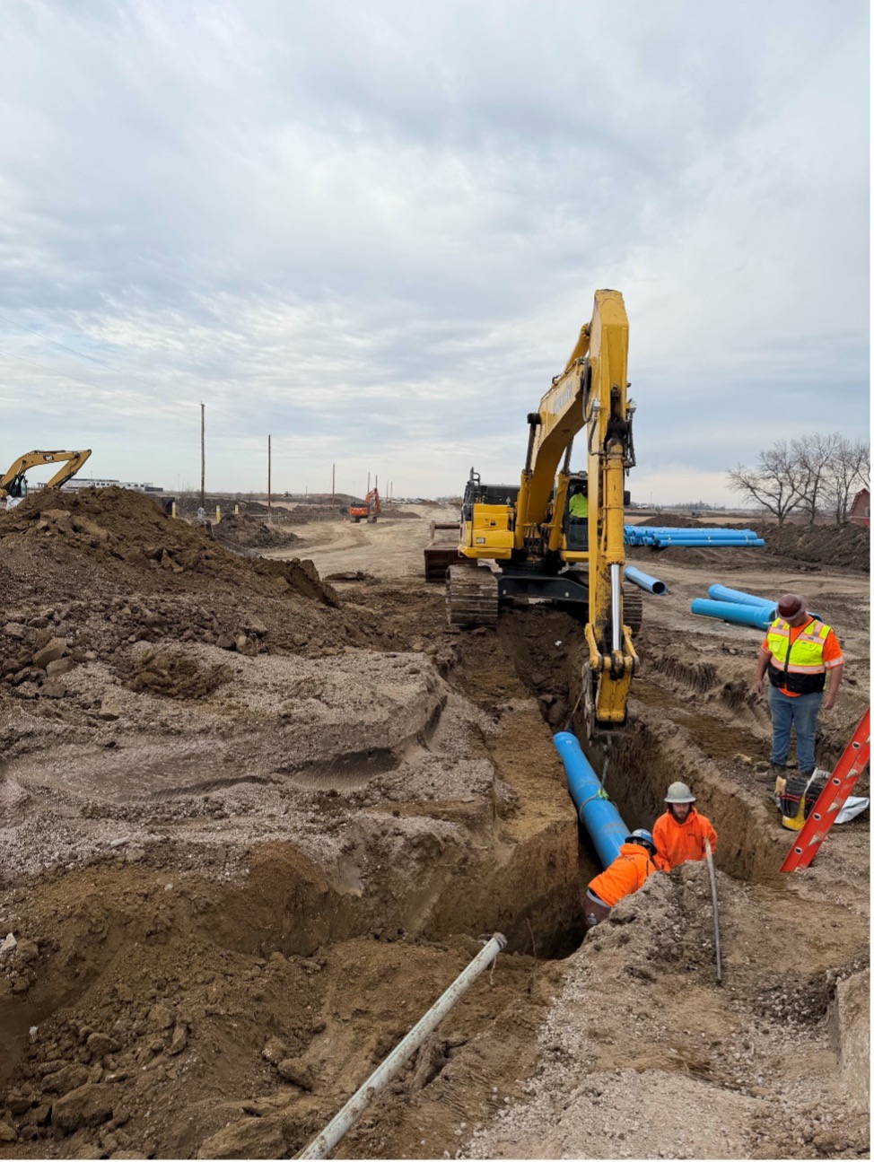 A crew installing blue watermain pipe into steel casing. 