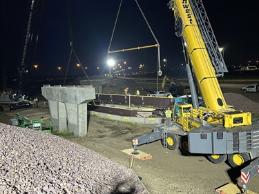 a crane installing a bridge girder over night
