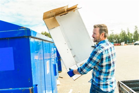 Man putting cardboard into a recycling bin