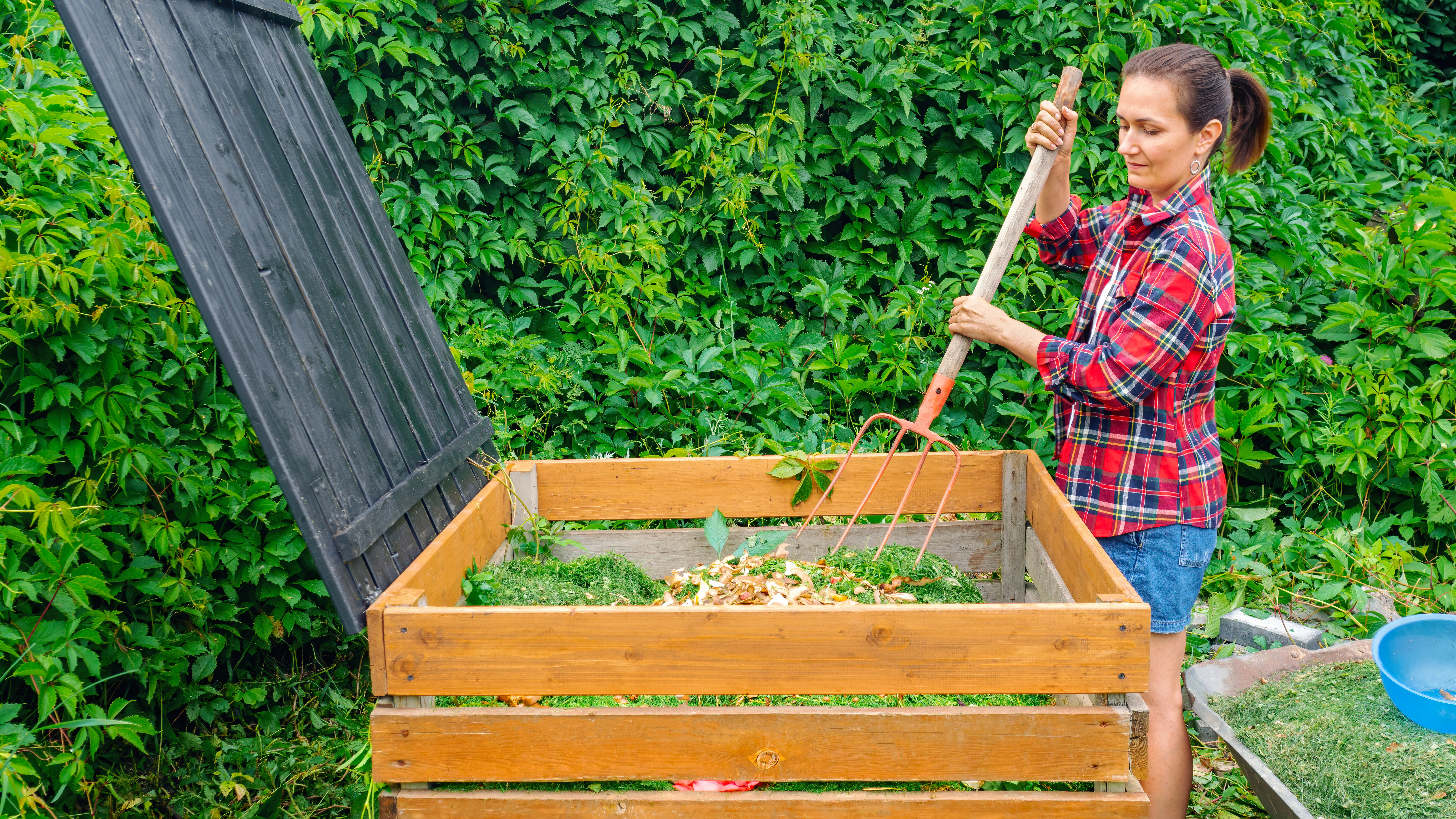A woman in a flannel shirt composting