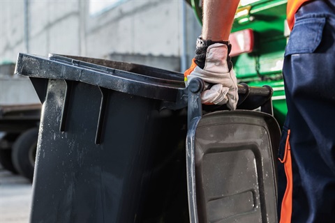 Man pulling an empty garbage bin